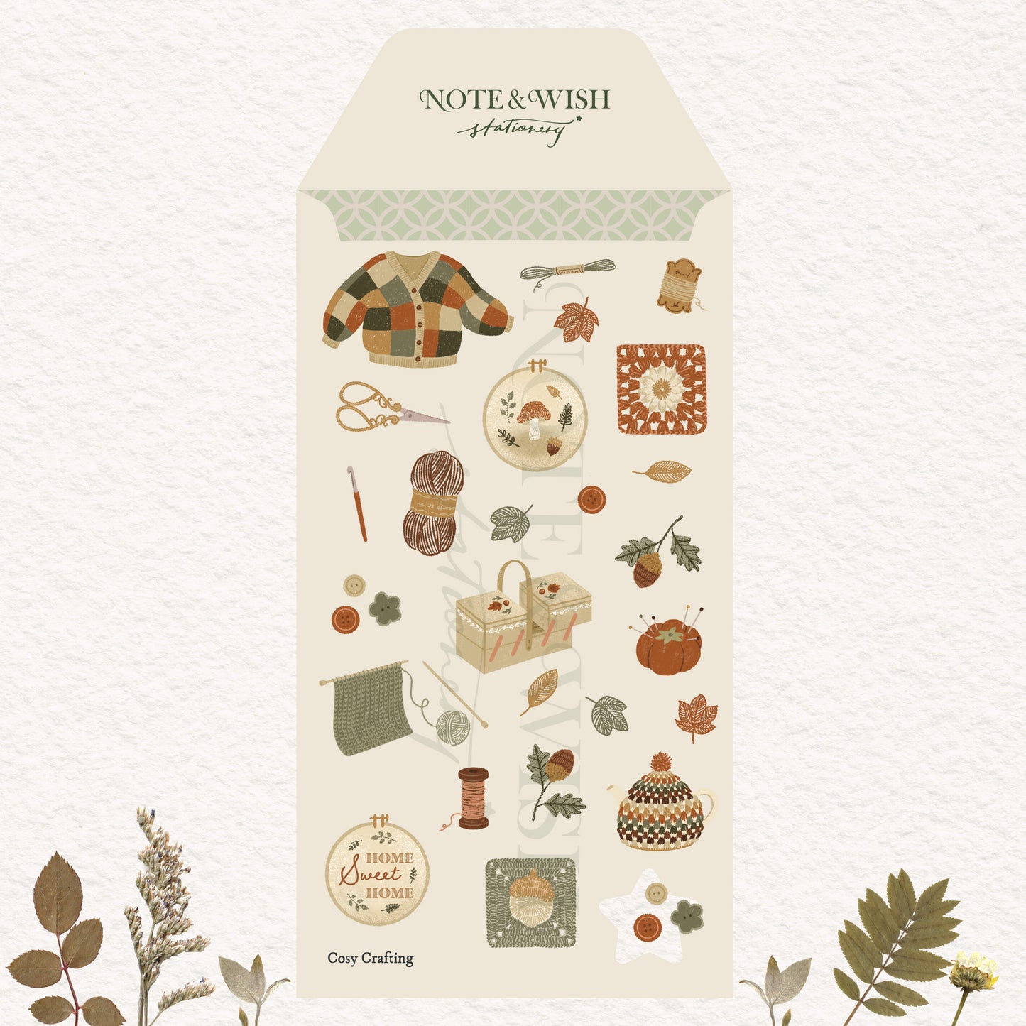 A tall cream-colored sticker sheet decorated with autumn-themed illustrations including a plaid cardigan, scissors, yarn, leaves, acorns and a teapot.
