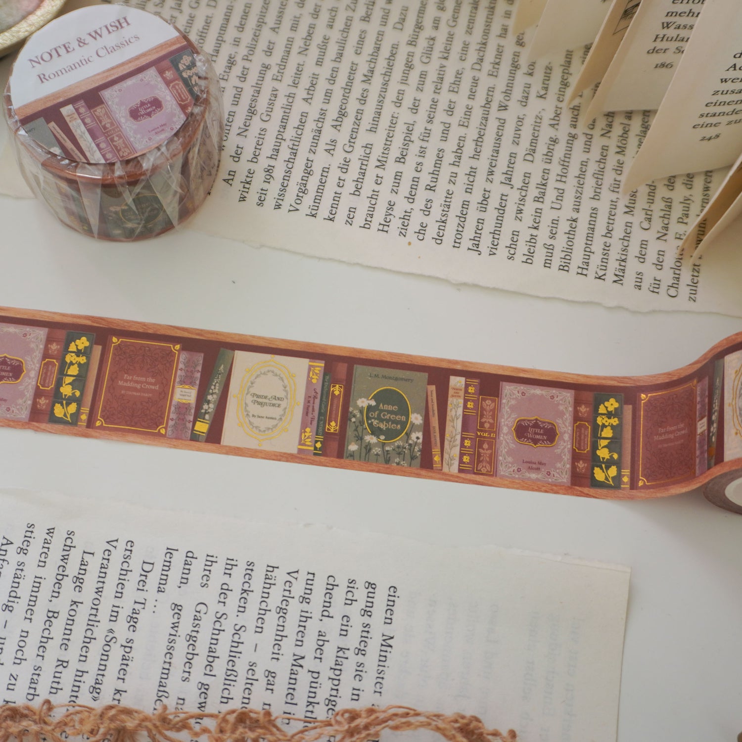 Close-up of hand-inked antique book spines on gold foiled washi tape, featuring titles such as pride and prejudice, little woman and anne of green gables. Designed in the UK and hand drawn by Rebecca. 