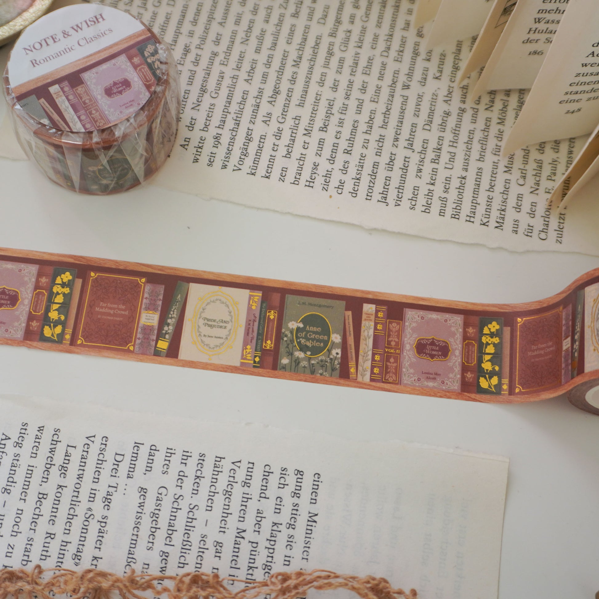 Close-up of hand-inked antique book spines on gold foiled washi tape, featuring titles such as pride and prejudice, little woman and anne of green gables. Designed in the UK and hand drawn by Rebecca. 