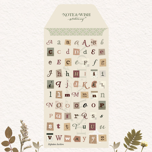 A decorative lettering sheet from Note & Wish called Alphabet Archive, featuring vintage-style mixed-case alphabet stickers in muted earthy tones on a cream envelope-shaped backing, with botanical illustrations at the bottom.