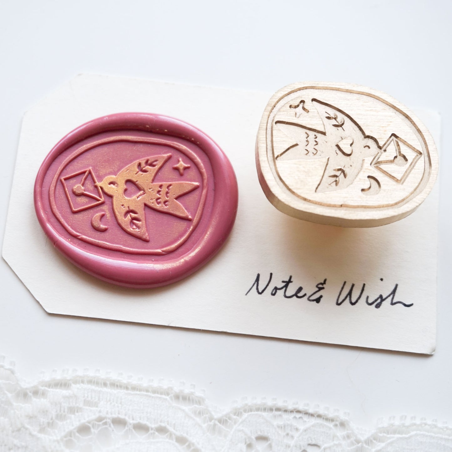 A wax seal stamp set featuring a pink wax seal impression with a bird and envelope design
