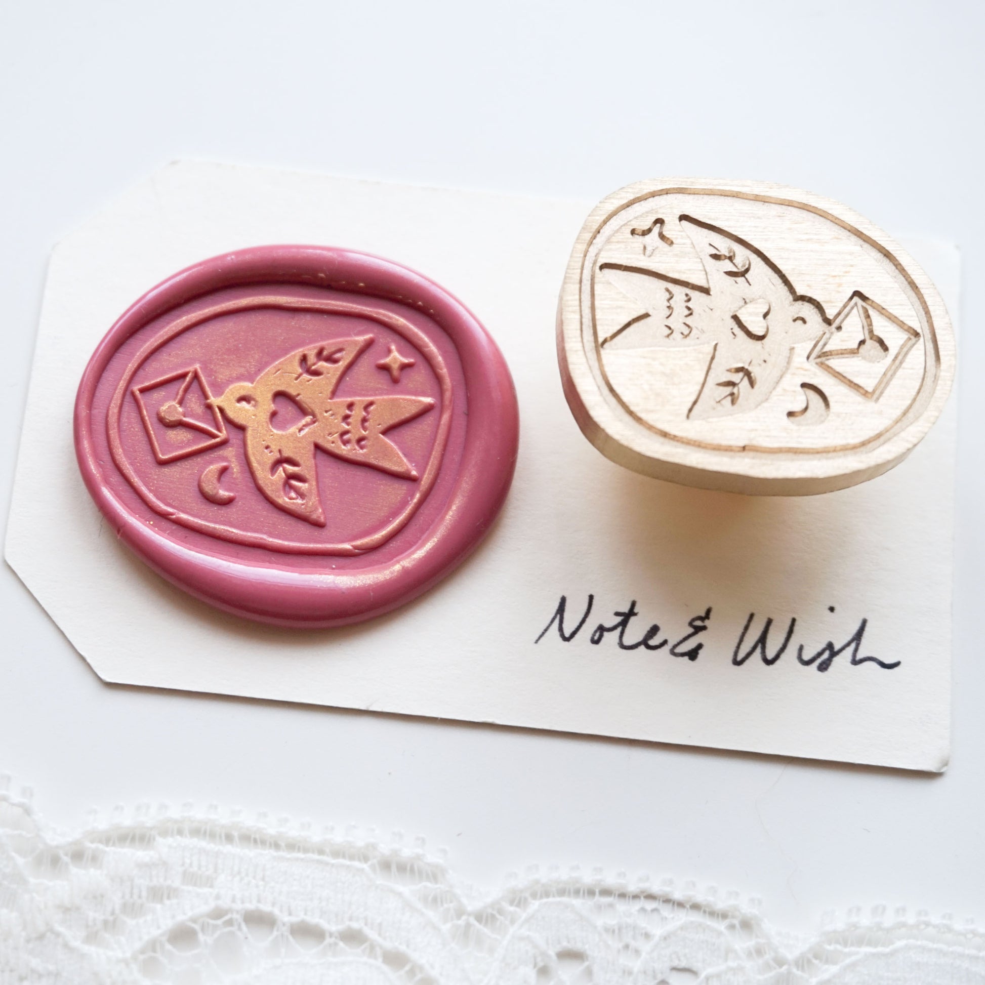A wax seal stamp set featuring a pink wax seal impression with a bird and envelope design