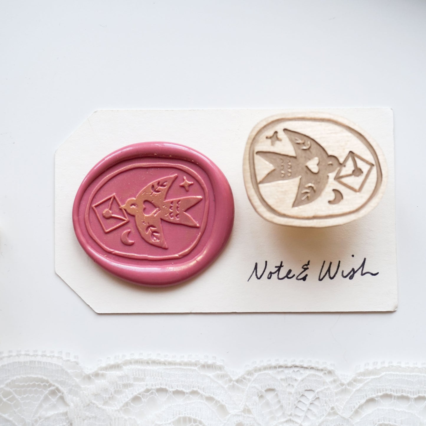 A wax seal stamp set featuring a pink wax seal impression with a bird and envelope design