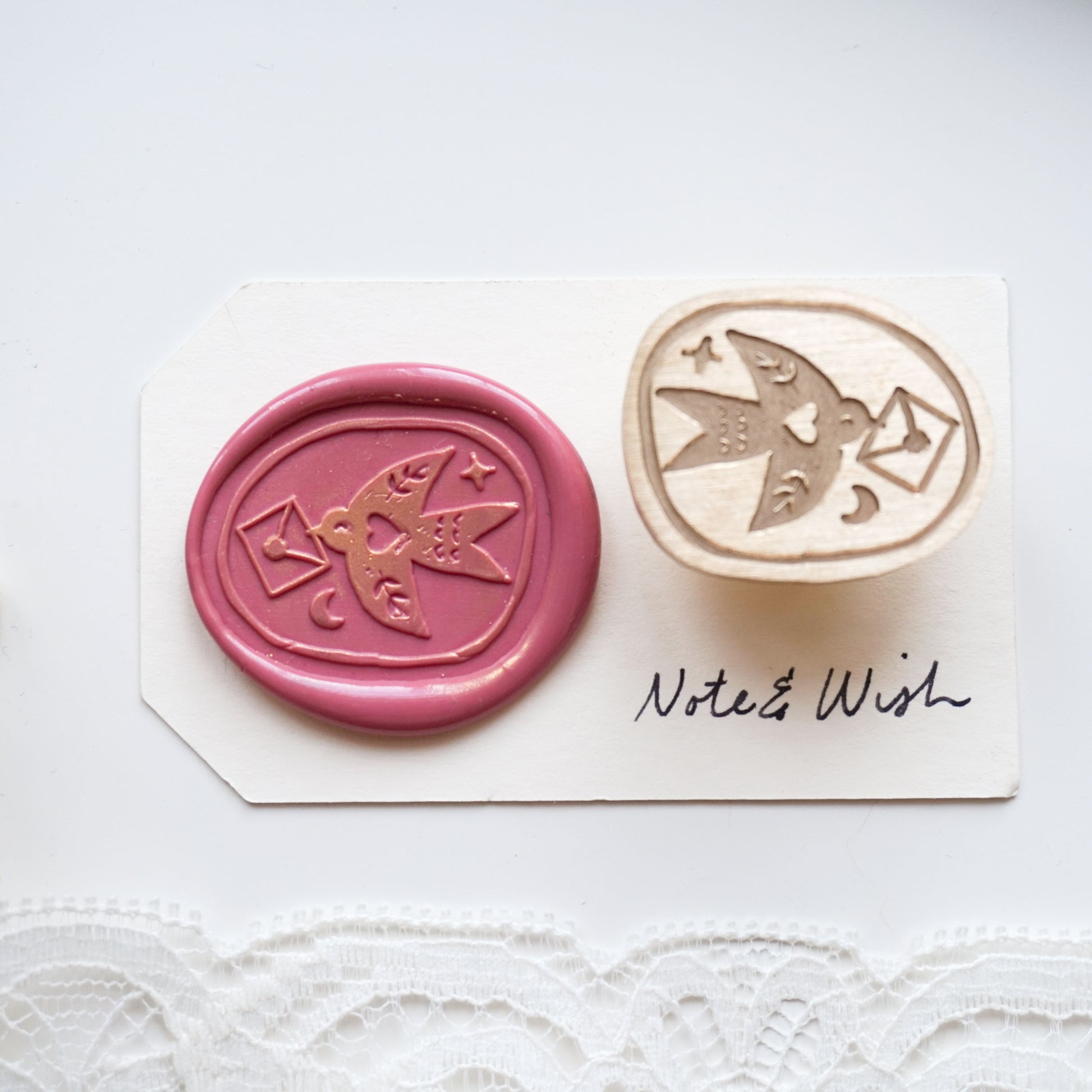 A wax seal stamp set featuring a pink wax seal impression with a bird and envelope design