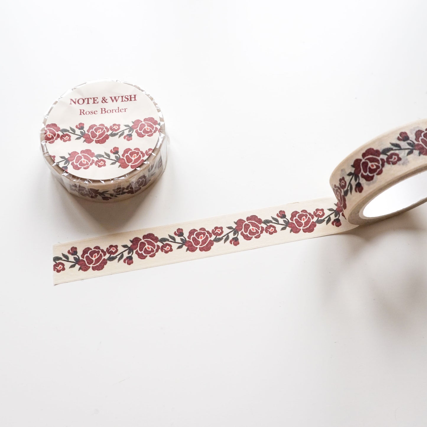 A roll of decorative washi tape with a repeating rose border pattern