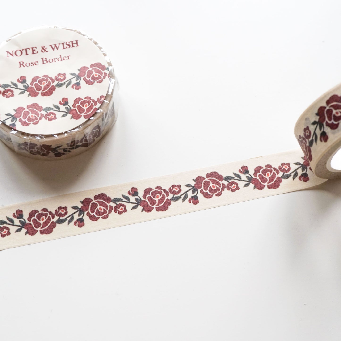 A roll of washi tape with a rose border pattern